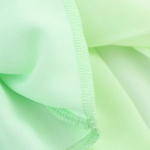 Macro shot of mint green chiffon fabric texture with clean overlock stitched edges