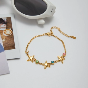 Fashionable gold starfish bracelet with colorful zircon stones on a clean white background