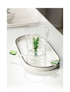 Detailed view of handmade glass cup with lily of the valley sculpture and glass stir spoon