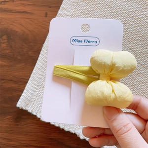 Detail of yellow pleated bow hair clip with light green alligator base on display card