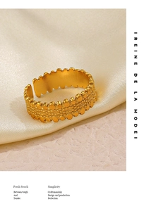 Detailed view of golden open ring featuring a textured beaded surface and wide band