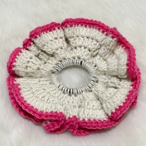 Detail of handmade crochet hair scrunchie in white and vibrant pink ruffle edge