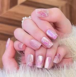 Detail of pink cat-eye press-on nails with marble texture and pearl ring accents