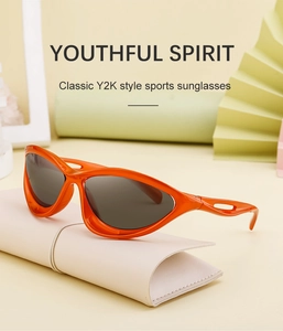 Close-up of bright orange Y2K sports sunglasses with cut-out temple details and dark lenses
