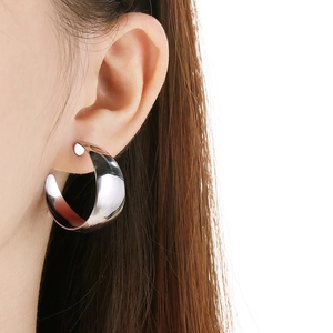 Close-up of model wearing silver polished wide C-shape stainless steel earrings