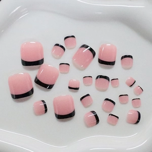 Classic pink press-on toenails with black French tips displayed on a white tray
