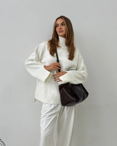 Detailed close-up of white turtleneck sweater with ribbed cuffs and split sleeves