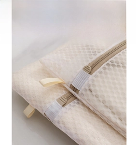 Detail of honey mesh laundry bag featuring an auto-lock zipper and gray pull tab