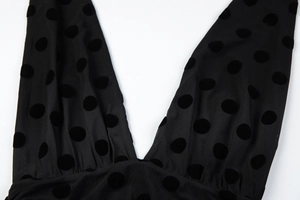 Detail of sheer mesh fabric with black velvet polka dots and sexy deep V-neckline cut