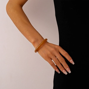 Close-up of translucent amber resin bangle bracelet on model wrist with minimalist style
