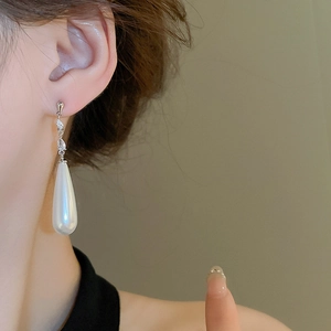 Close-up of elegant teardrop pearl earrings with shimmering cubic zirconia on model