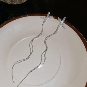 Détail macro de boucles d'oreilles pampilles argentées avec zircon en forme de X