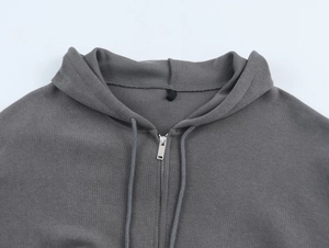 Detailed close-up of a gray ribbed hoodie with a high-quality metal zipper and knit fabric