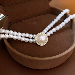 Détail d'un collier de perles double rang avec fermoir strass doré dans son écrin