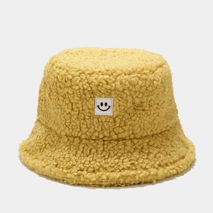 Detail of yellow teddy fleece bucket hat featuring a smiley face patch and plush texture