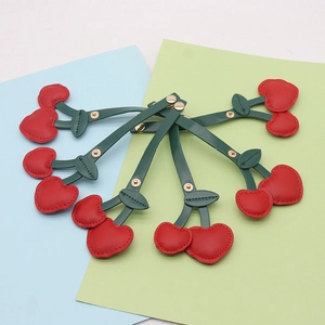 Detail of red cherry PU leather cable organizers with golden metal snap fasteners