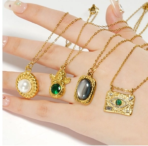 Close-up of four gold stainless steel necklaces with natural stone and angel pendants