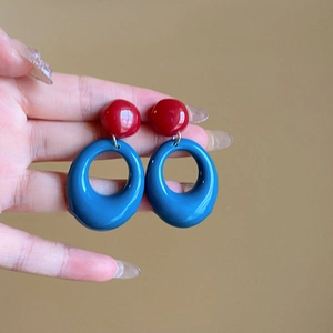 Detail view of retro caramel color hoop earrings with glossy red and blue contrast design