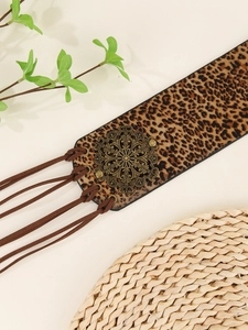 Close-up of leopard print wide belt with vintage engraved metal buckle and long tassels