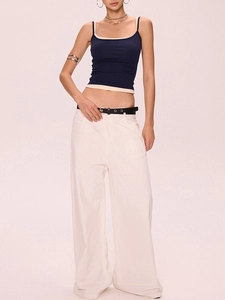 Détail de caraco côtelé bleu marine et pantalon large blanc avec ceinture noire