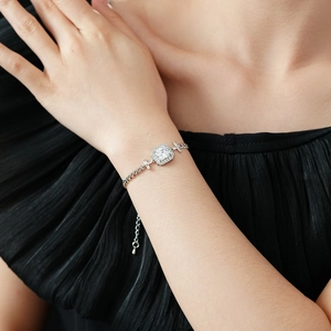Détail d'un bracelet en argent avec cristal carré et charmes en croix au poignet