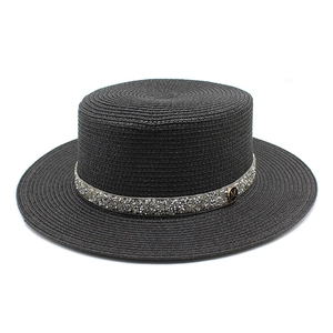 Close-up of black straw boater hat featuring rhinestone band and gold M logo