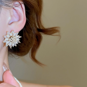 Detail of 18k gold plated flower stud earrings with zircons and pearls on model