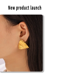 Detailed view of gold triangular earring with pleated texture worn on model's ear