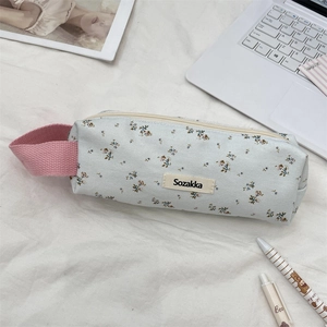Close-up of floral pencil case with pink fabric handle on a study desk scene