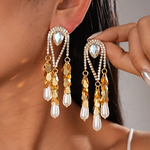 Détail de boucles d'oreilles plaquées or 18 carats avec strass et glands de perles