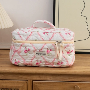 Detail of quilted cosmetic bag featuring pink rose patterns and wide top carry handle