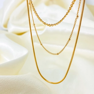 Detailed close-up of triple-layered gold necklaces with twist, bead, and snake chains