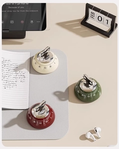Magnetic mechanical kitchen timers in cream, green, and red on a modern desk setup