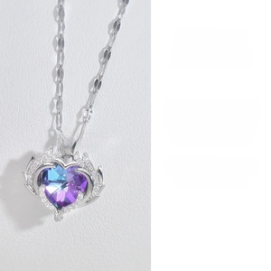 Detailed close-up of heart-shaped crystal pendant with purple gradient and wing design