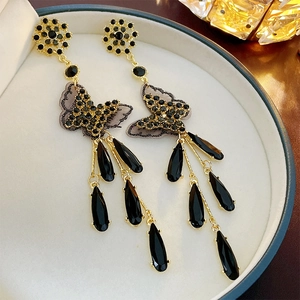 Detail view of long tassel earrings featuring black crystal butterflies and golden metal