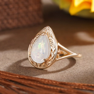 Detailaufnahme von Opal-Ring in Birnenform mit hohlgeschnitzten Blättern am goldenen Band