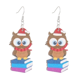 Pendientes de madera con forma de búho, libros y gorro de Navidad sobre fondo blanco puro