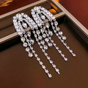 Close-up of silver long tassel earrings with sparkling crystals on brown velvet
