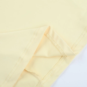 Close-up of double stitching and edge craftsmanship on the light yellow stretch dress