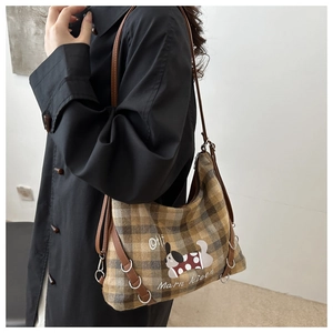 Detail of vintage brown plaid underarm bag with dog embroidery on a black coat