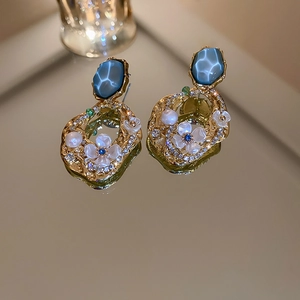 Vue macro de boucles d'oreilles vintage dorées avec gemmes bleues et détails floraux