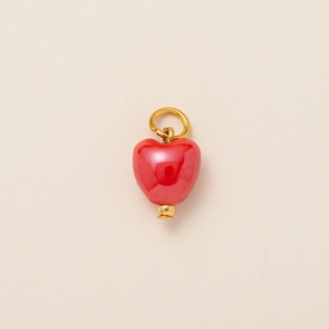 Gros plan détaillé d'un petit pendentif coeur rouge plaqué or sur fond beige