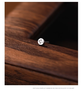 Macro shot of silver S925 sterling silver cross screw head earrings on wood texture