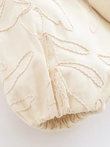 Vue détaillée de la broderie florale sur la manche de la veste en coton crème