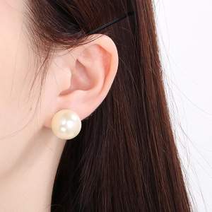 Close-up of model wearing a large cream white pearl stud earring with elegant luster