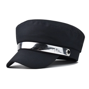 Detail view of black baker boy hat featuring a silver metal band with M letter embossing