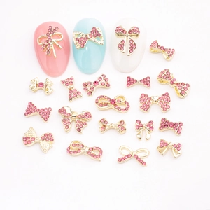 Pink rhinestone bow nail art charms with gold metal bases in various elegant designs