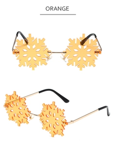 Detail view of snowflake-shaped rimless sunglasses with orange lenses and golden metal frame