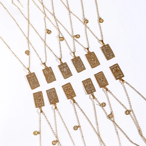 Flat lay of 12 gold tarot zodiac necklaces with rectangular pendants on white background