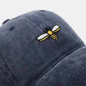 Macro view of high-quality bee embroidery on navy blue washed cotton baseball cap